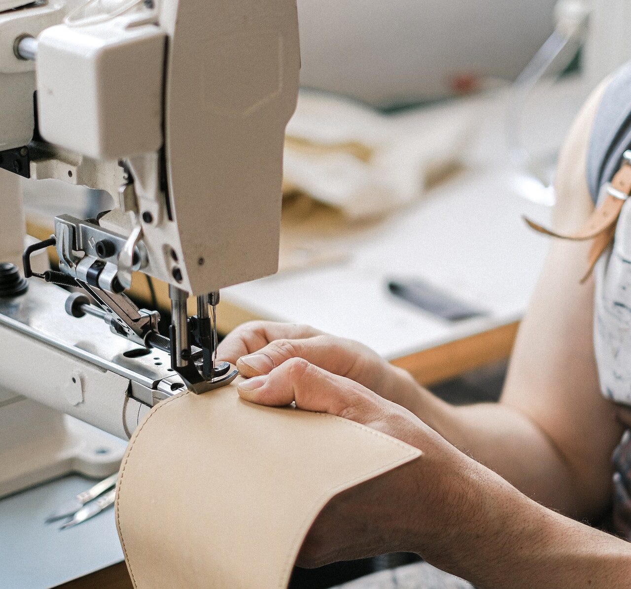 worker on a sewing machine with leather