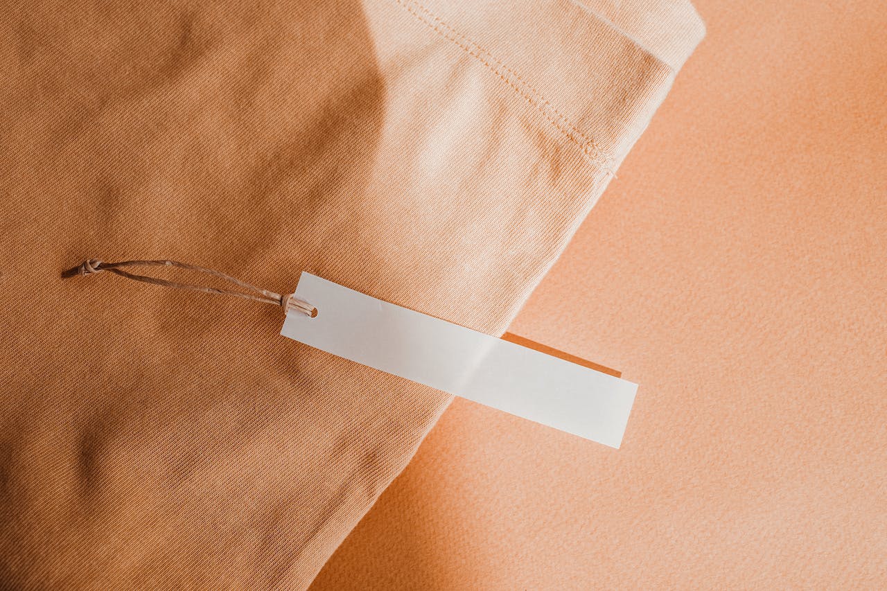close up photo of orange garment on an orange background with hangtag on top of it