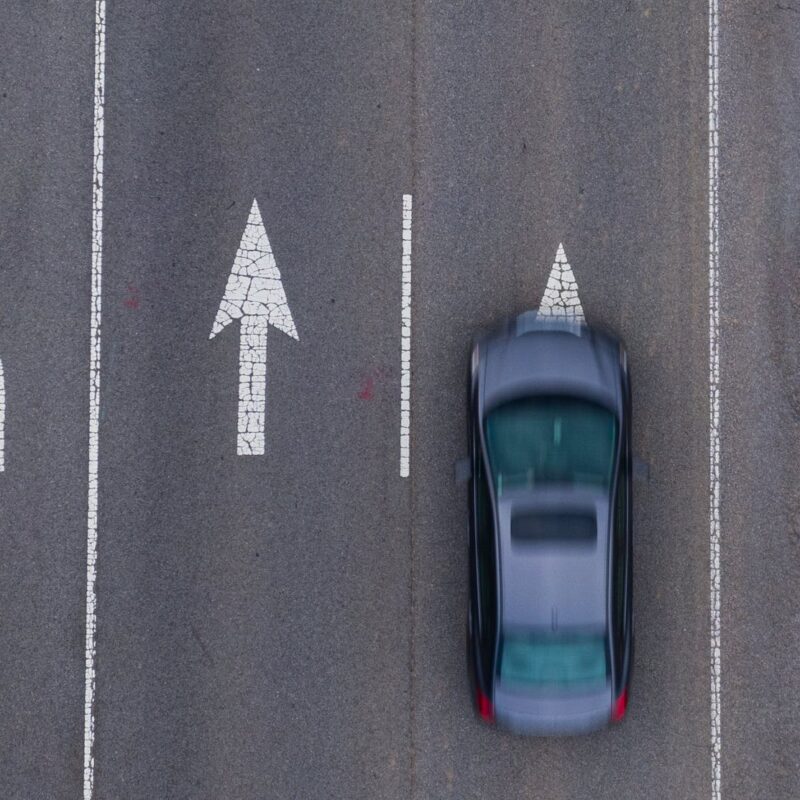 car driving on a road with 4 different direction arrows