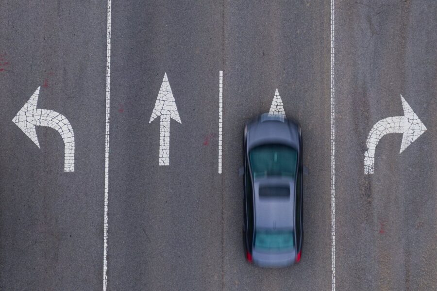 car driving on a road with 4 different direction arrows
