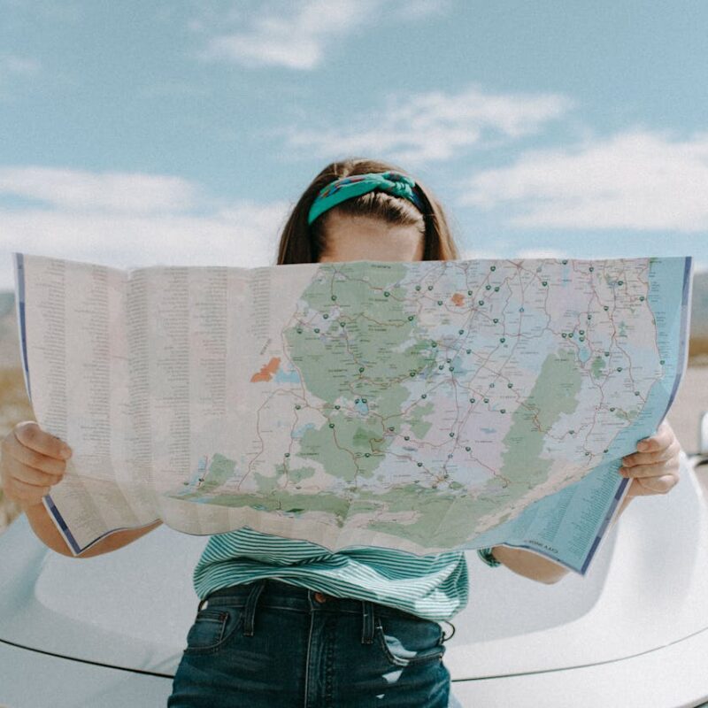 woman standing by her car looking at a map