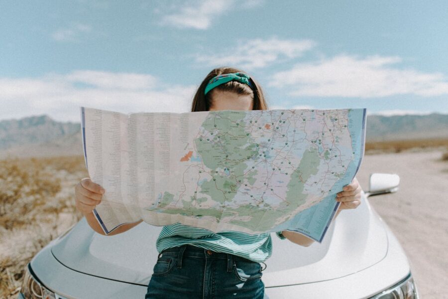 woman standing by her car looking at a map