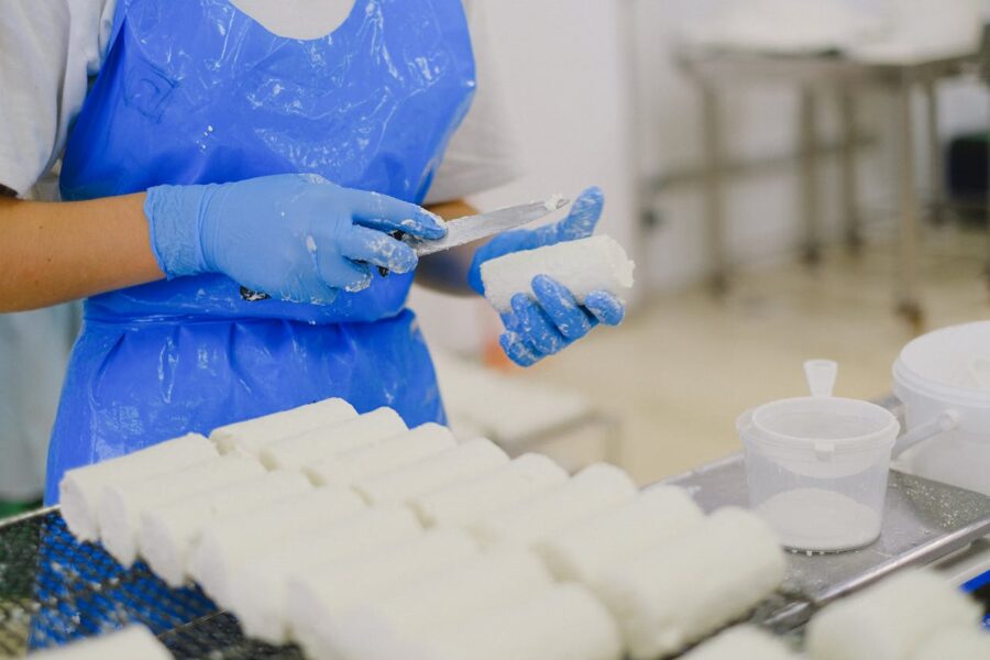 worker shaping cheese in factory